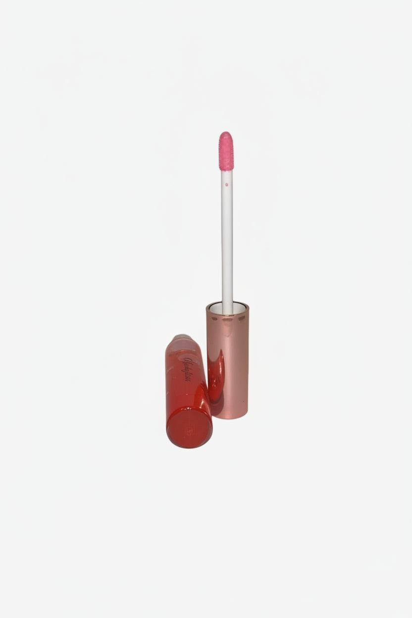 Pink lip gloss with a white applicator on a light surface